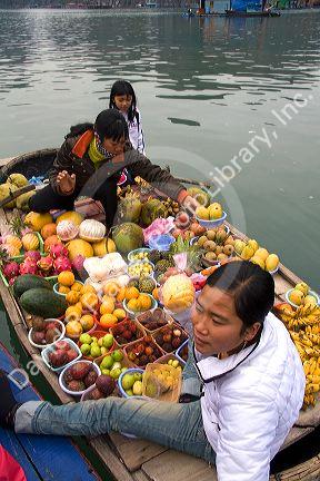 Vietnamese boat vendors selling fruit in Ha Long Bay, Vietnam.