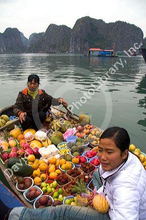 Vietnamese boat vendors selling fruit in Ha Long Bay, Vietnam.