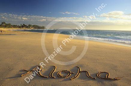 Aloha written in the sand on a Hawaiian beach.