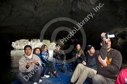 Tourists ride on a small boat viewing sea caves in Ha Long Bay, Vietnam.