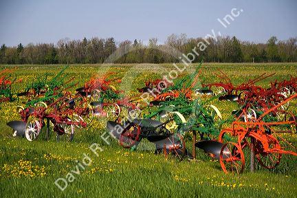 Colorfully painted antique plows on display at a farm near Corunna, Michigan, USA.