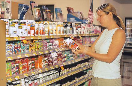 Woman shopping for vitamins in a grocery store.