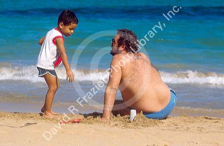 Father and son play in the sand at the beach in Pueto Rico.