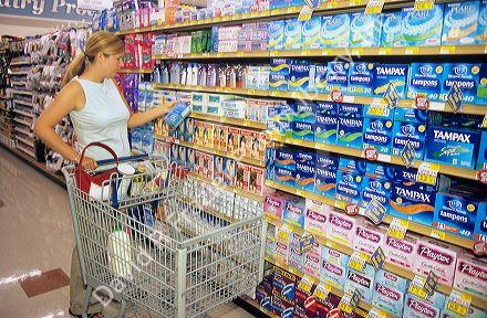 Woman shopping in the feminine hygene section of a grocery store.