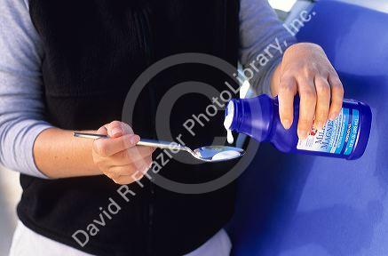 A person pouring milk of magnesia into a spoon.
