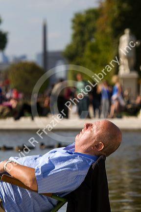 Man sunbathing near a fountain at the Tuileries Garden near the Lourve in Paris, France.