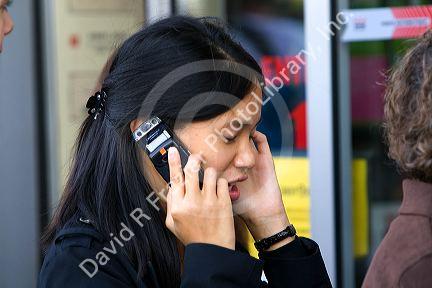 Asian female student talking on a cell phone in the Latin Quarter of Paris, France.