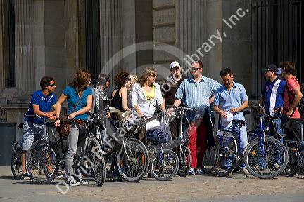 Tourists on bicycles in front of the Louvre Palace housing the Louvre Museum in Paris, France.