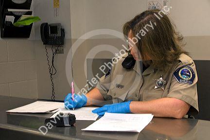 Booking agent taking inventory of an inmates personal property in a jail.