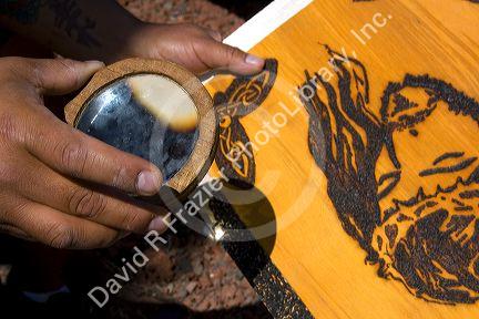 Sunlight being concentrated with a magnifying lens to burn a design into wood creating art. Cholula, Puebla, Mexico.