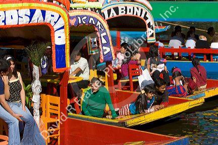 Colorful trajineras travel on the Xochimilco canals within Mexico City, Mexico.