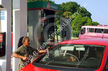 Mexican female attendant washing a car window at a full service gas station in Acapulco, Guerrero, Mexico.