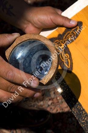 Sunlight being concentrated with a magnifying lens to burn a design into wood creating art. Cholula, Puebla, Mexico.