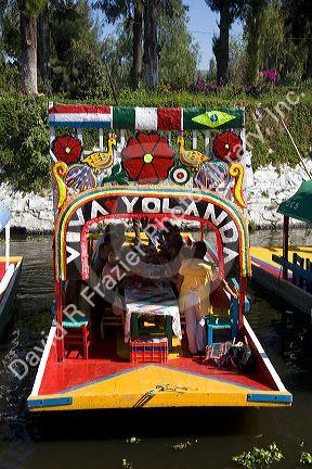 Colorful trajineras travel on the Xochimilco canals within Mexico City, Mexico.