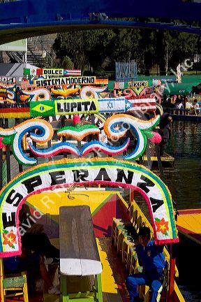 Colorful trajineras travel on the Xochimilco canals within Mexico City, Mexico.
