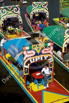 Colorful trajineras travel on the Xochimilco canals within Mexico City, Mexico.