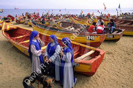 Nuns stand on the beach in front of fishing boats at Valparaiso, Chile.