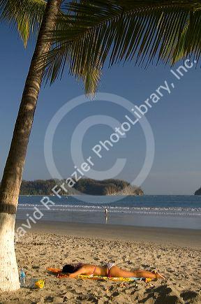 Woman sunbathing on the beach at Playa Samara, Costa Rica.
