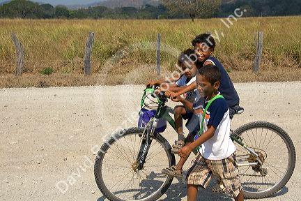 Costa Rican children ride a bicycle near the town of Nicoya, Costa Rica.
