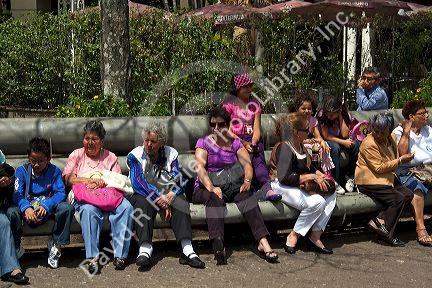 People sit on park benches in the city of San Jose, Costa Rica.