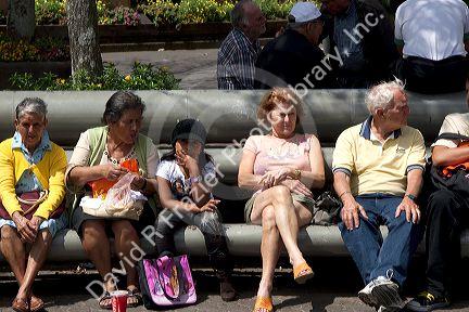 People sit on park benches in the city of San Jose, Costa Rica.