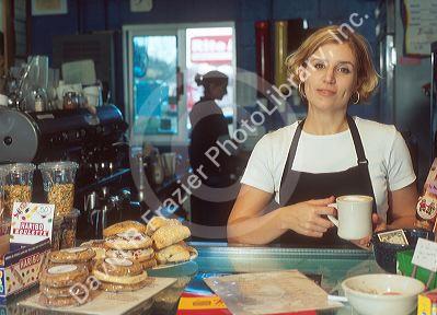 Female employee at a coffee shop standing at the couter. MR