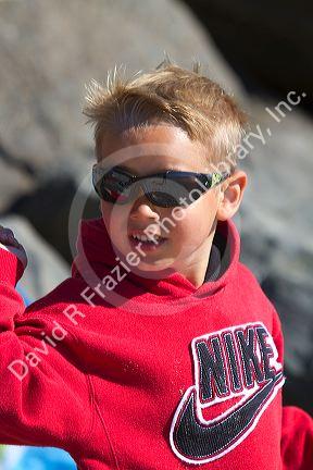 Boy wearing sunglasses for ultraviolet protection along the D River in Lincoln City, Oregon, USA.