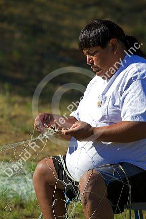 Yakama Nation indian repairing fishing nets at Celilo Village on the Columbia River, Oregon, USA. MR
