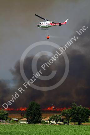 Helicopter with water bucket performing aerial firefighting on a wildfire in Eagle, Idaho, USA.