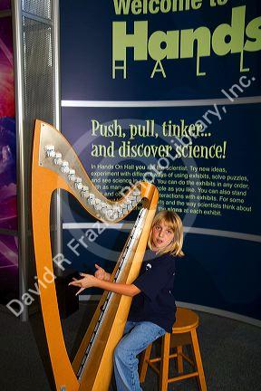 Child playing an electronic stringless harp at the Gulf Coast Exploreum Science Center in Mobile, Alabama, USA.