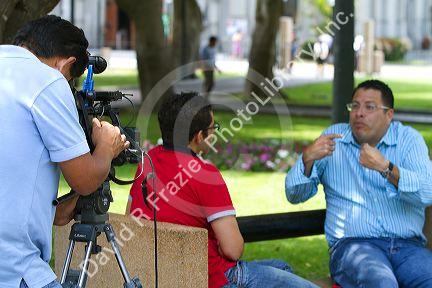 Television camera recording men having an interview in Central Park of the Miraflores district of Lima, Peru.