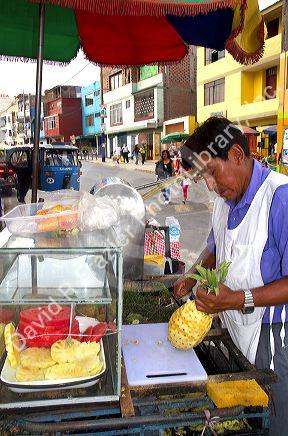 Street vendor carving a pineapple in Lima, Peru.