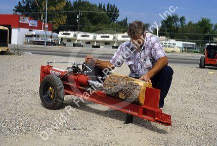 A man operates a gaspowered log splitter.