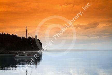 A morning view of Spilt Rock Lighthouse with sailboat and mist on Lake Superior, Minnesota, USA.