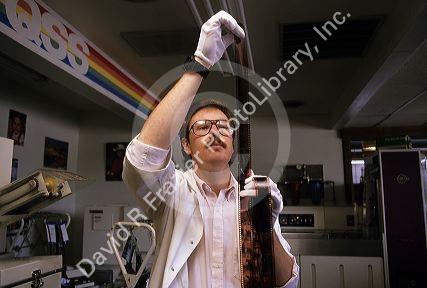 A lab technician working with negative film in a photo lab.