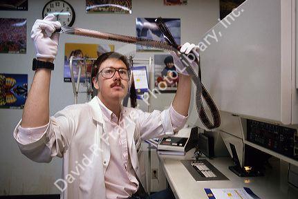 A lab technician working with negative film in a photo lab.