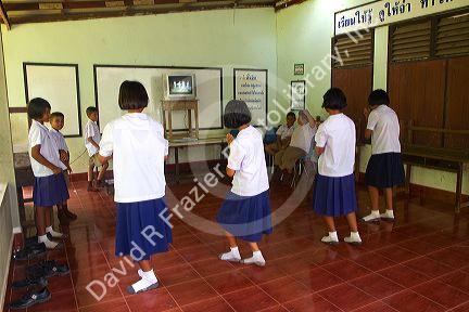 Thai elementary students dance with direction from a television at school on the island of Ko Samui, Thailand.