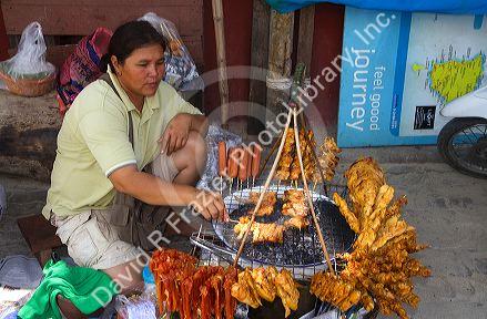Food vendor grilling meat over a charcoal fire at Chaweng beach on the island of Ko Samui, Thailand.