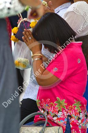 Woman praying at the Temple of the Emerald Buddha located within the precincts of the Grand Palace, Bangkok, Thailand.