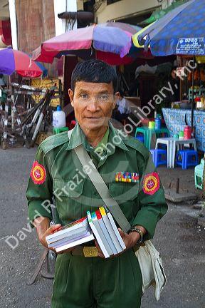 Burmese military veteran in uniform selling books on the street in (Rangoon) Yangon, (Burma) Myanmar.
