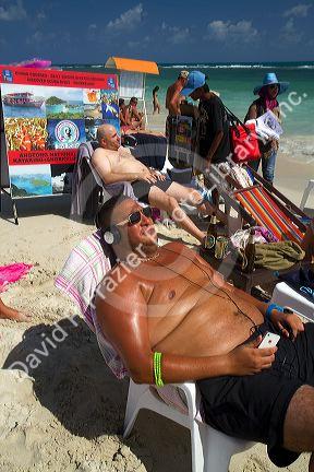 Man wearing head phones while sun tanning at Chaweng beach on the island of Ko Samui, Thailand.