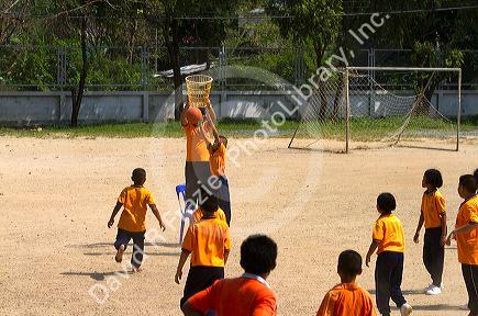 Students play basketball at a Thai elementary school playground on the island of Ko Samui, Thailand.