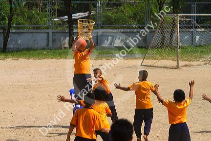 Students play basketball at a Thai elementary school playground on the island of Ko Samui, Thailand.