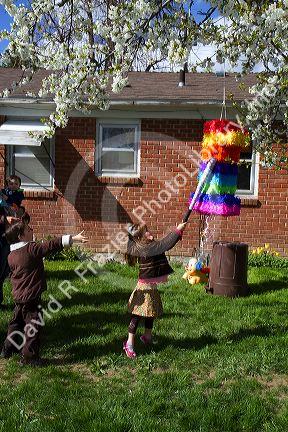 Children hitting a pinata at a hispanic childs birthday party in Boise, Idaho, USA.