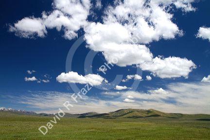 Cumulus clouds and blue sky over green fields near Pine, Idaho, USA.