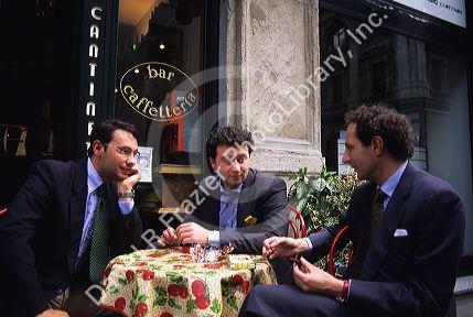Italian businessmen sitting at a table at an outdoor cafe.