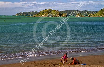 People on the beach at Bay of Islands at the town of Paihia, North Island, New Zealand.