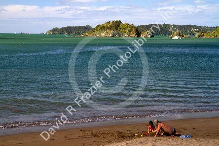 People on the beach at Bay of Islands at the town of Paihia, North Island, New Zealand.
