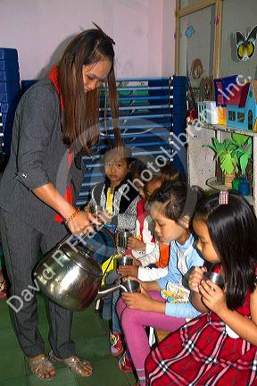 Young students recieve hot water for noodles at an elementary school in Da Lat, Vietnam.