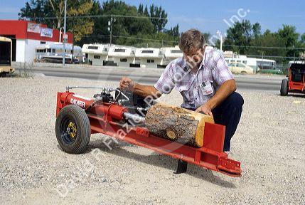 A man uses a gas powered hydrolic log splitter.
